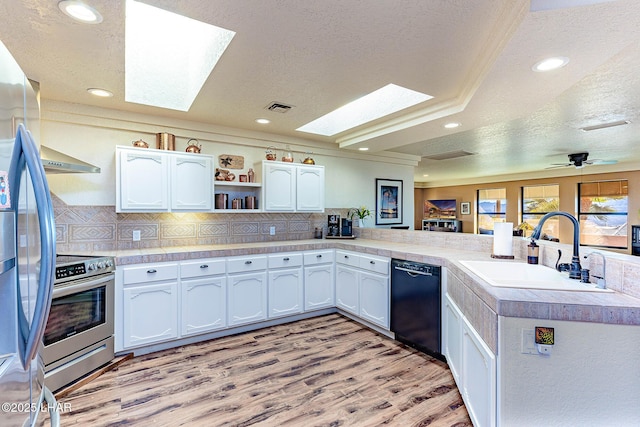 875 Wallingford Pl, Lake Havasu City, AZ 86406 - kitchen with a skylight, a textured ceiling, appliances with stainless steel finishes, light wood-style floors, and tasteful backsplash