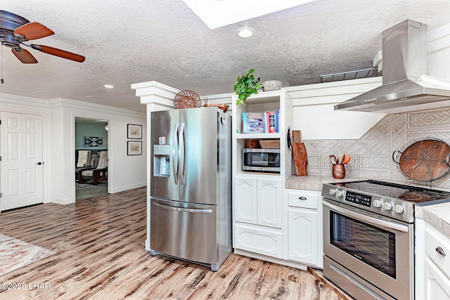 875 Wallingford Pl, Lake Havasu City, AZ 86406 - kitchen with appliances with stainless steel finishes, wall chimney exhaust hood, light wood-style flooring, white cabinets, and a ceiling fan