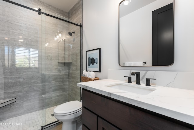 bathroom featuring vanity, a shower with shower door, and toilet