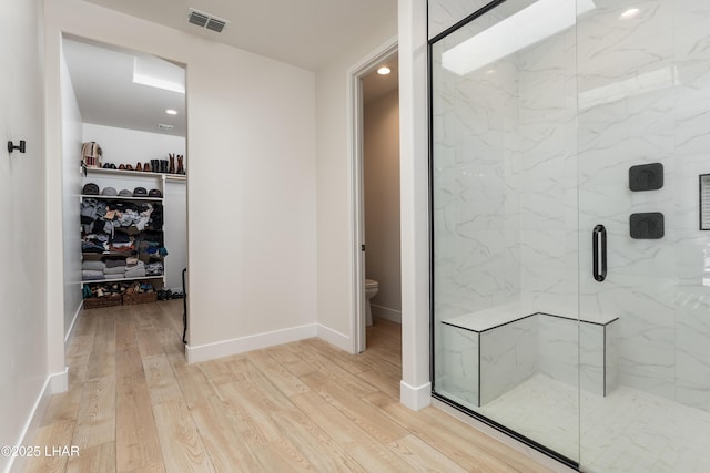 bathroom featuring a shower with door, hardwood / wood-style floors, and toilet