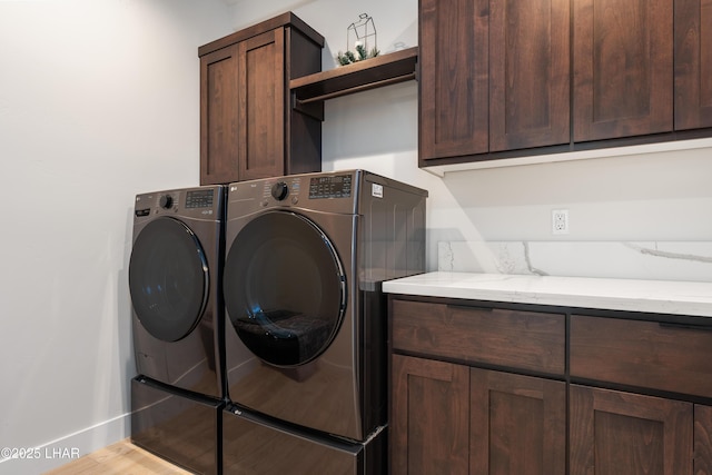 washroom with cabinets, washer and dryer, and light hardwood / wood-style flooring