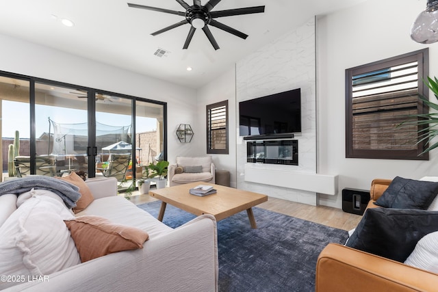 living room with lofted ceiling, a fireplace, light hardwood / wood-style floors, and ceiling fan