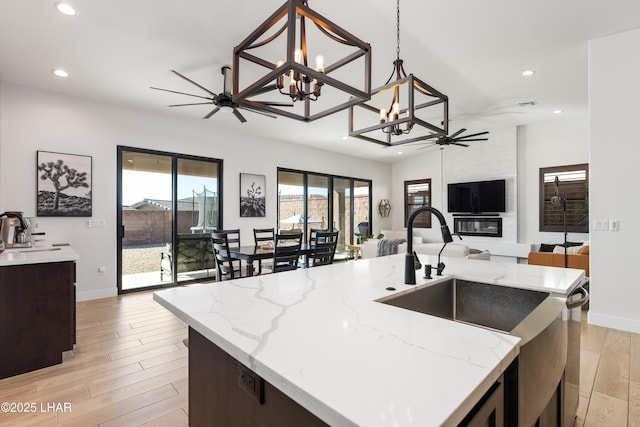 kitchen with pendant lighting, ceiling fan, a kitchen island with sink, and light hardwood / wood-style flooring