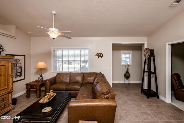 tiled living area featuring ceiling fan, visible vents, and baseboards