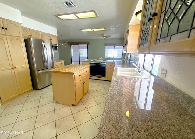 kitchen featuring sink, light tile patterned floors, stainless steel appliances, a kitchen island, and light brown cabinets