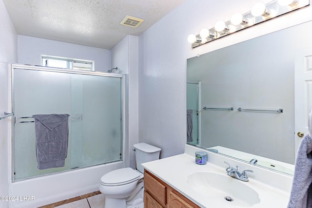 full bathroom with shower / bath combination with glass door, tile patterned flooring, vanity, toilet, and a textured ceiling