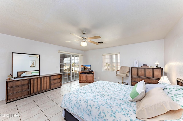 bedroom featuring ceiling fan, light tile patterned floors, and a textured ceiling