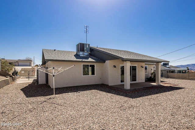 rear view of house with stucco siding, central air condition unit, fence, a shingled roof, and a patio area