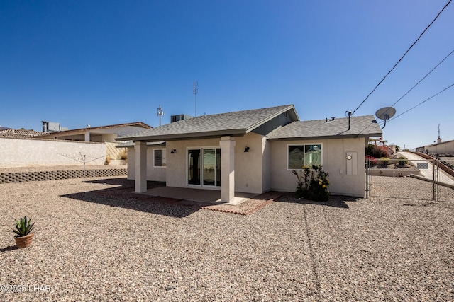 rear view of house featuring stucco siding, a patio, a fenced backyard, and a shingled roof