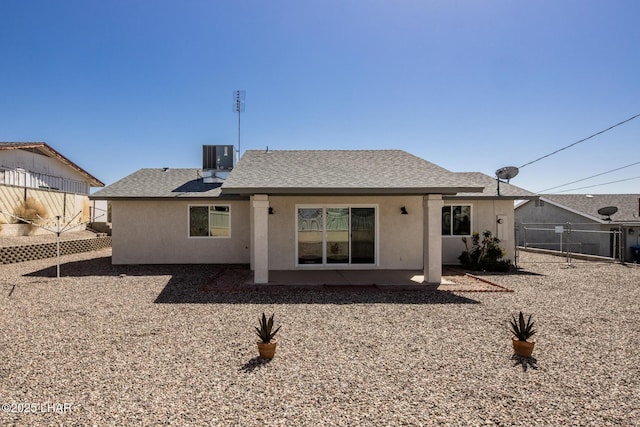 rear view of property featuring stucco siding, a patio area, roof with shingles, and fence