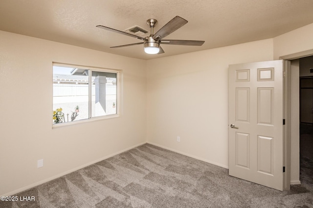 carpeted spare room featuring visible vents, a textured ceiling, baseboards, and a ceiling fan