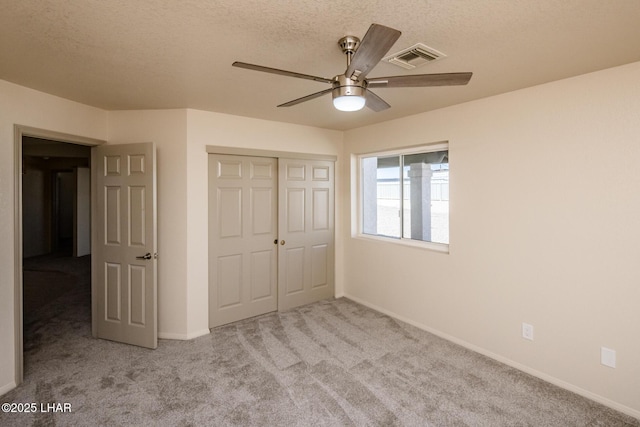 unfurnished bedroom with visible vents, ceiling fan, carpet, a closet, and a textured ceiling