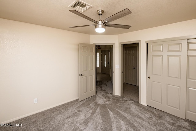 unfurnished bedroom with visible vents, a textured ceiling, carpet flooring, baseboards, and ceiling fan