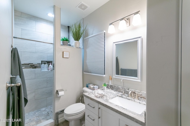 full bath featuring toilet, vanity, tiled shower, and visible vents