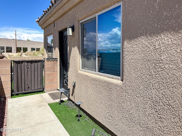 view of home's exterior with stucco siding and fence