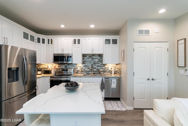 kitchen featuring visible vents, stainless steel appliances, tasteful backsplash, a sink, and a center island