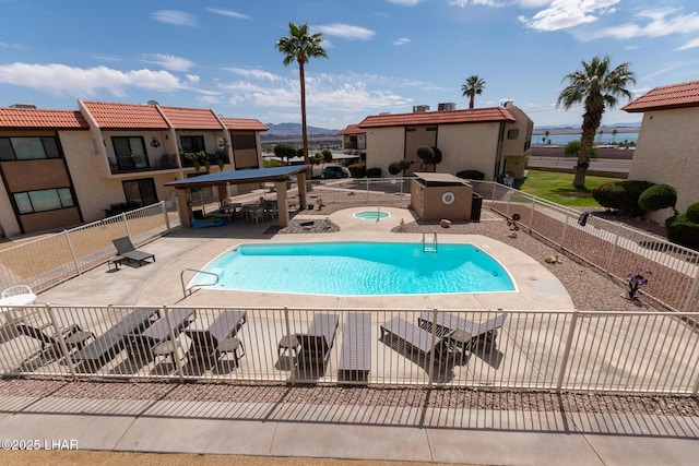 community pool featuring a patio, a hot tub, and fence