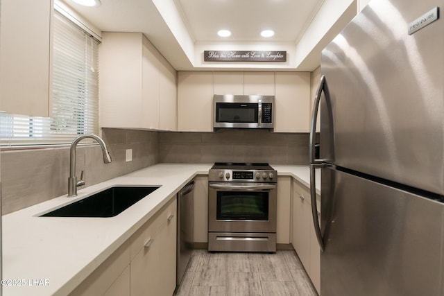 kitchen featuring backsplash, crown molding, a sink, light countertops, and stainless steel appliances