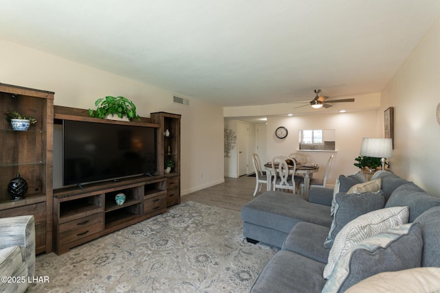 living area with ceiling fan, visible vents, and baseboards