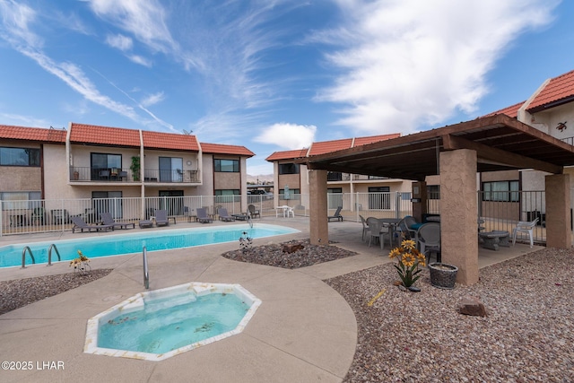 pool with fence, a patio, and a hot tub