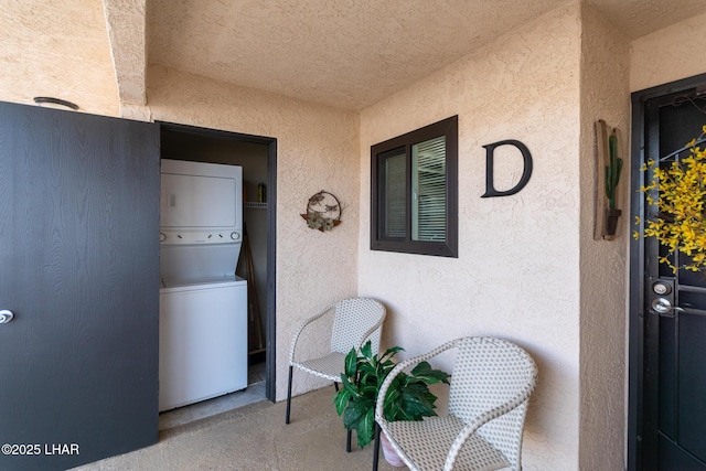 exterior space featuring stacked washer and clothes dryer and stucco siding