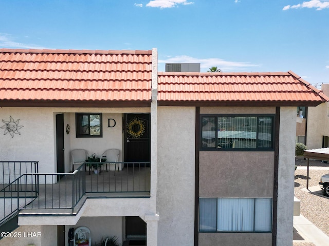 exterior space with stucco siding and a tile roof