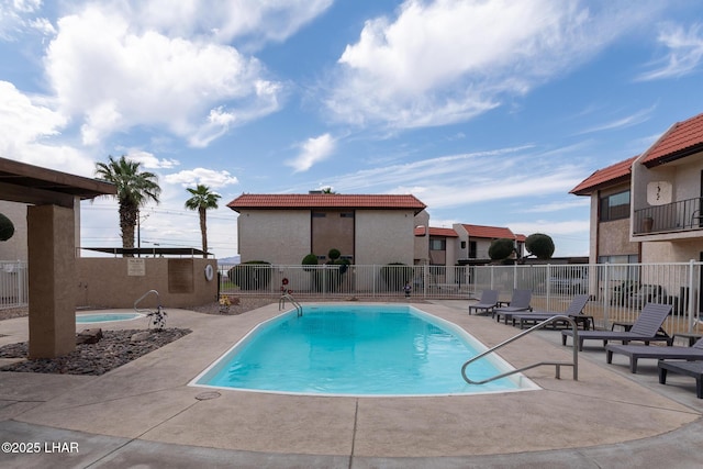 community pool with fence and a patio area
