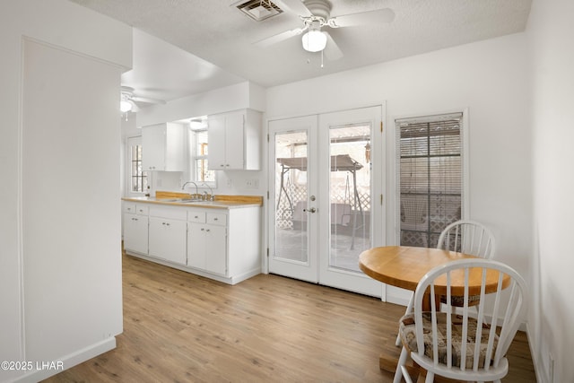 kitchen featuring french doors, a ceiling fan, visible vents, light countertops, and light wood-style flooring