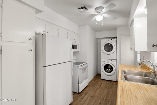 kitchen with ceiling fan, stacked washer / drying machine, a sink, light countertops, and white appliances