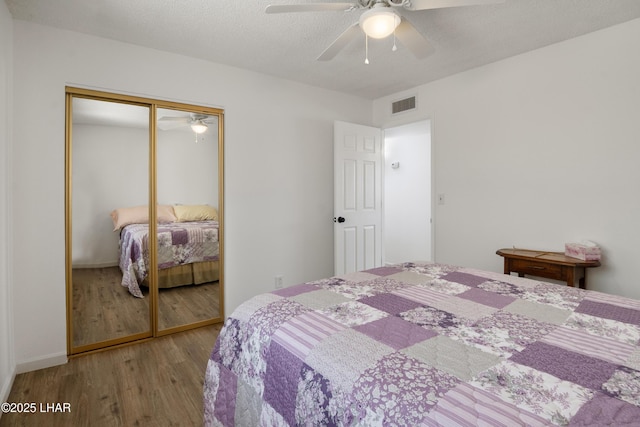 bedroom with a ceiling fan, a closet, wood finished floors, and visible vents