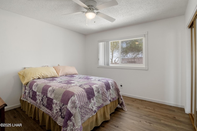 bedroom featuring baseboards, ceiling fan, a textured ceiling, and wood finished floors