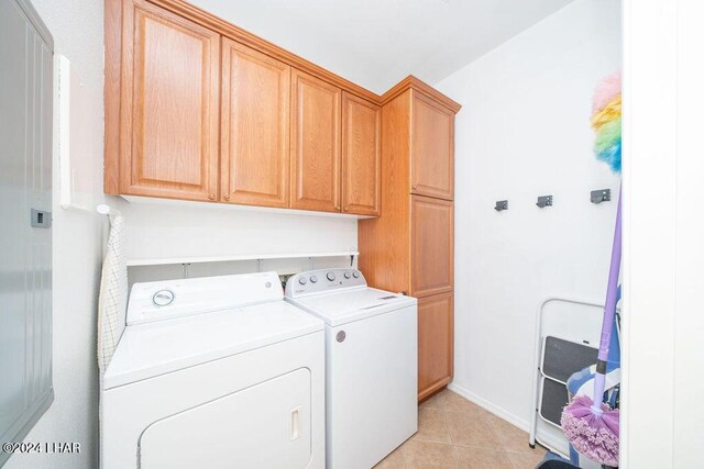 laundry room featuring washer and clothes dryer, cabinets, and light tile patterned flooring