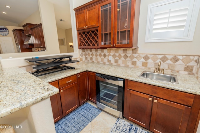 kitchen featuring backsplash, glass insert cabinets, a sink, light stone countertops, and beverage cooler