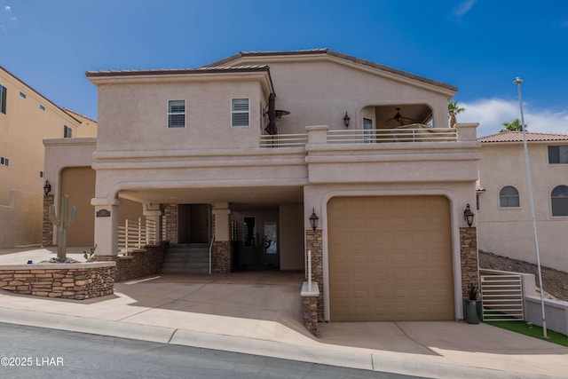 view of front facade featuring a ceiling fan, concrete driveway, a balcony, stone siding, and stucco siding