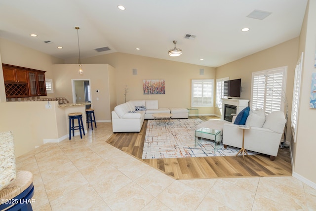 living area featuring a glass covered fireplace, visible vents, lofted ceiling, and light tile patterned floors