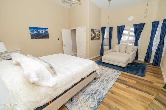 bedroom with a high ceiling, baseboards, and wood finished floors