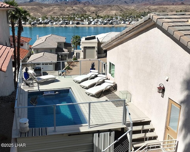 view of swimming pool with a water and mountain view and a hot tub