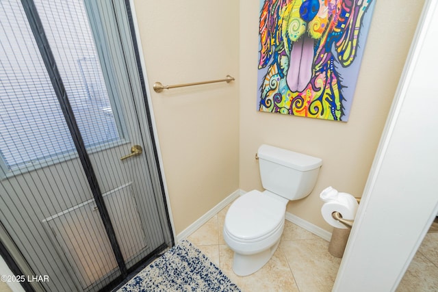 bathroom with tile patterned flooring, baseboards, and toilet