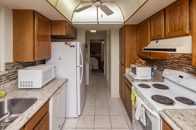 kitchen with brown cabinetry, white appliances, range hood, a ceiling fan, and light tile patterned floors