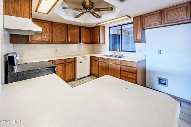 kitchen with electric stove, sink, light tile patterned floors, white dishwasher, and a tray ceiling