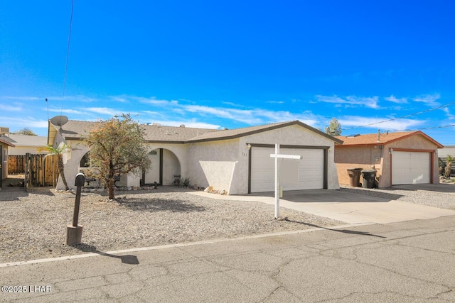 view of front of house with concrete driveway, an attached garage, fence, and stucco siding