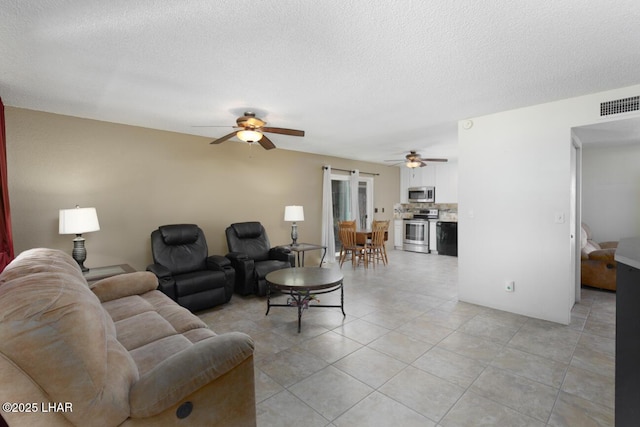 living area featuring a textured ceiling, ceiling fan, light tile patterned floors, and visible vents