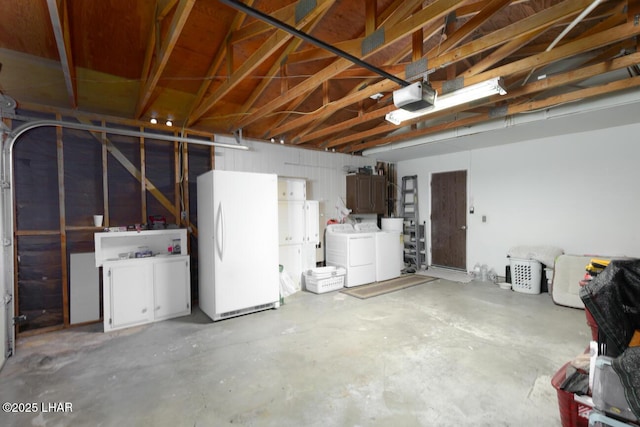 garage with a garage door opener, freestanding refrigerator, and separate washer and dryer