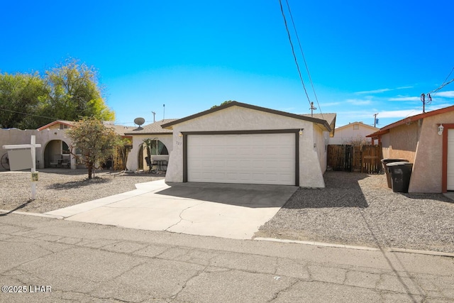 view of front of house featuring a garage, driveway, fence, and stucco siding