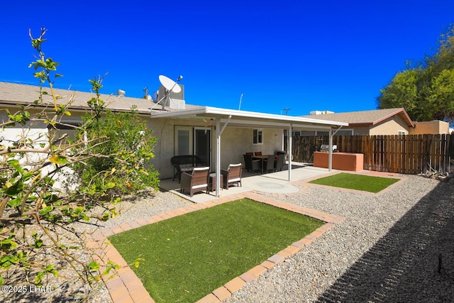 rear view of house featuring a lawn, fence, a patio, and stucco siding