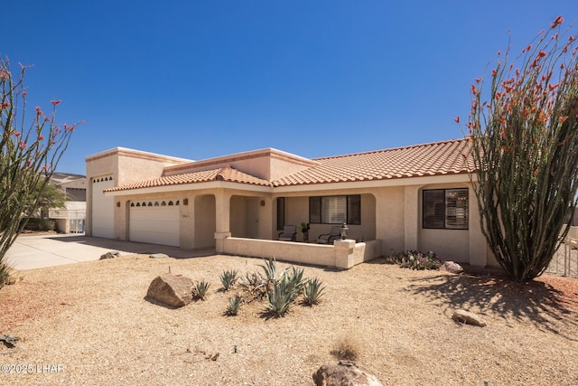 view of front of house with an attached garage, a tile roof, concrete driveway, and stucco siding