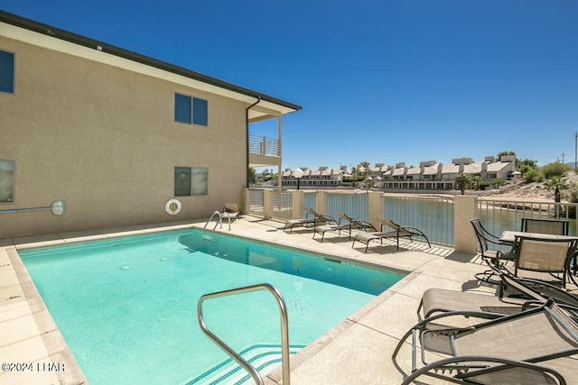 view of pool with a water view and a patio area