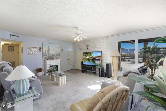 carpeted living room featuring ceiling fan and a textured ceiling