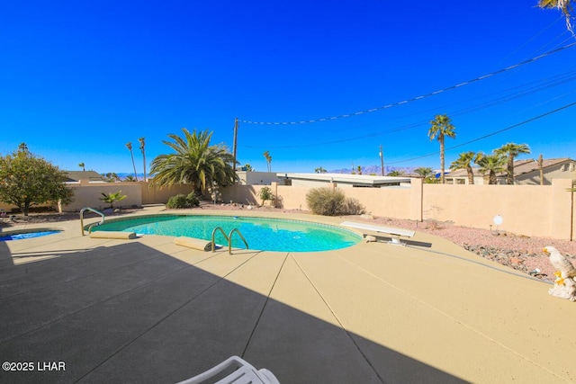 view of swimming pool featuring a diving board and a patio