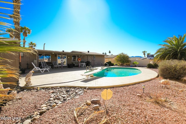 view of swimming pool with a diving board and a patio